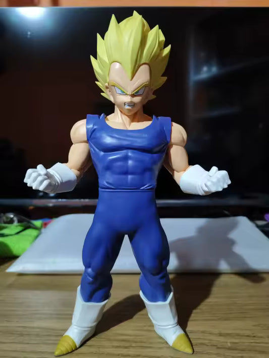 Figura Vegeta — Grandista IV de Banpresto en PVC, con cabello rubio de Super Saiyan y traje azul, sobre mesa de madera frente a pantalla negra.